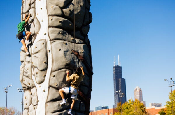 Students climb and outdoor, pop-up climbing wall at RecFest with the Chicago skyline in the background, Willow Tower