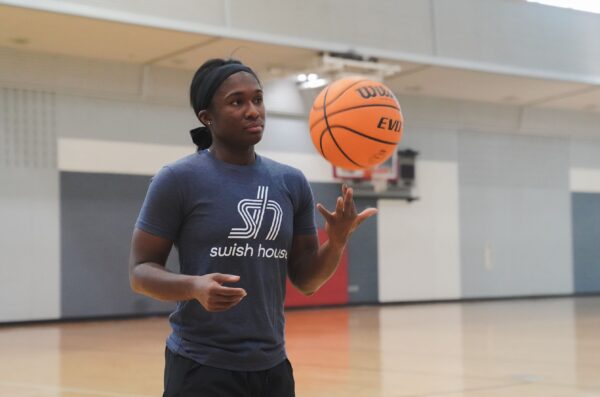 student spins basketball on finger wearing a swish house shirt