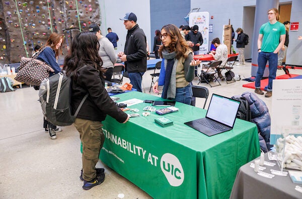 a student stands at the UIC Sutsainability table during Rec LIVE in front of the Climbing Wall